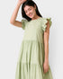 Woman wearing a light green dress with ruffled sleeves against a white background