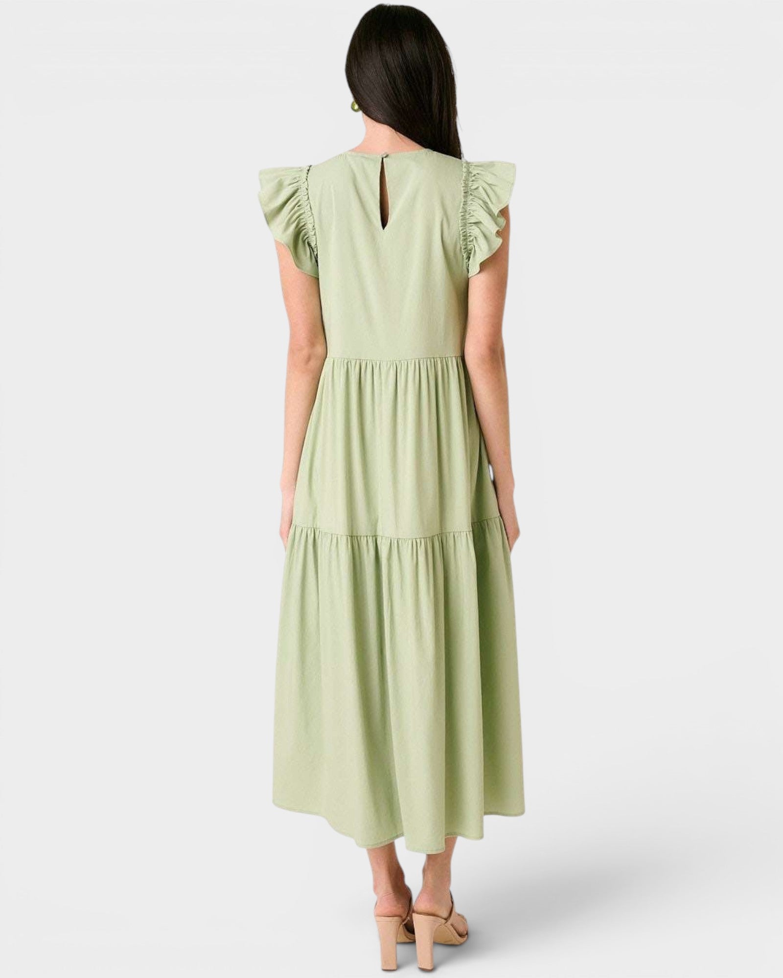 Woman wearing a light green dress with ruffled sleeves on a white background