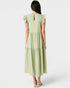 Woman wearing a light green dress with ruffled sleeves on a white background