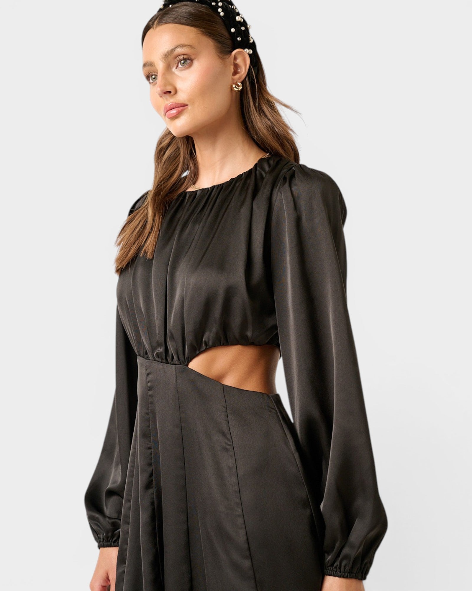 Woman wearing a black dress with cut-out design on a light gray background