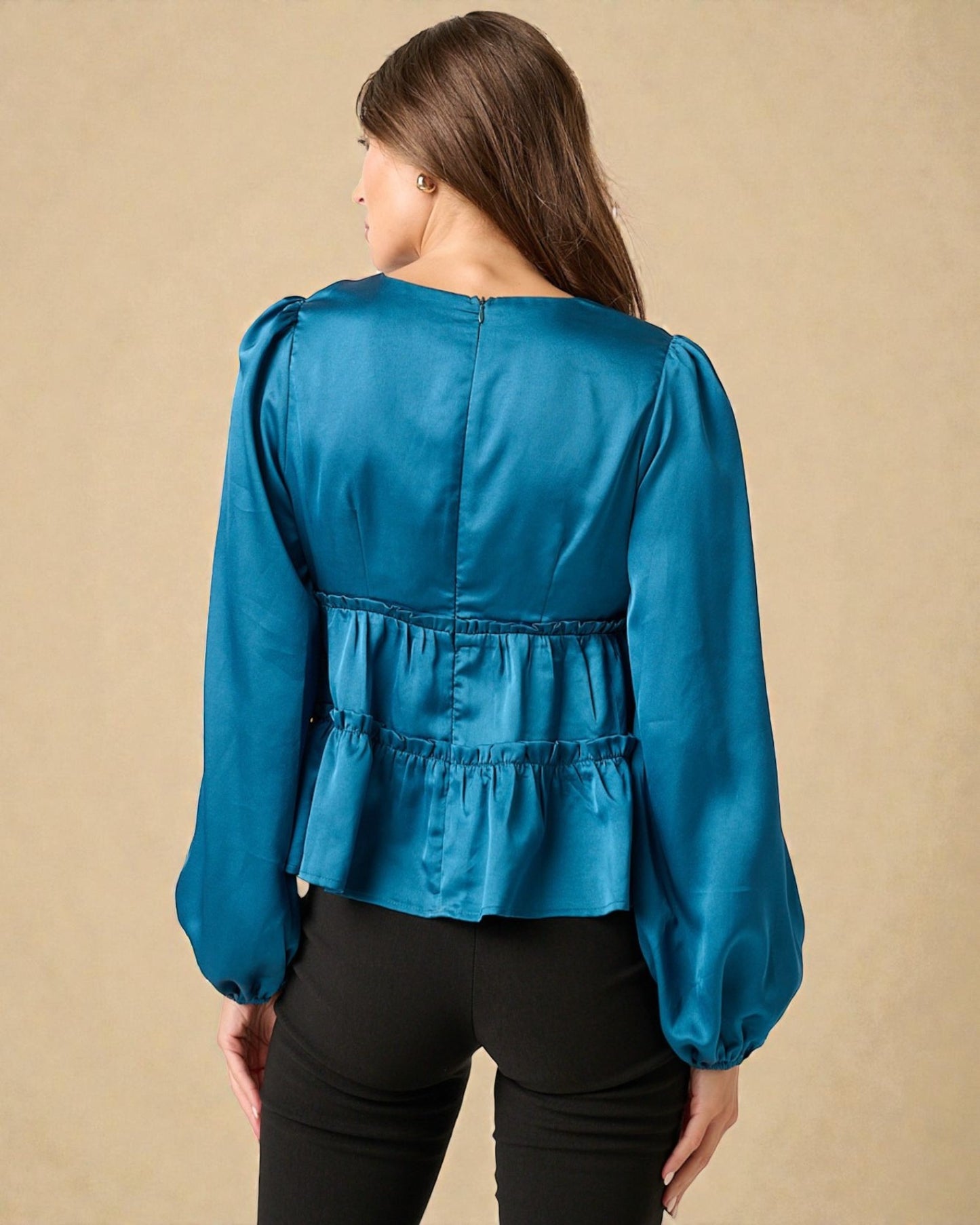 Woman wearing a blue blouse with puffed sleeves against a beige background