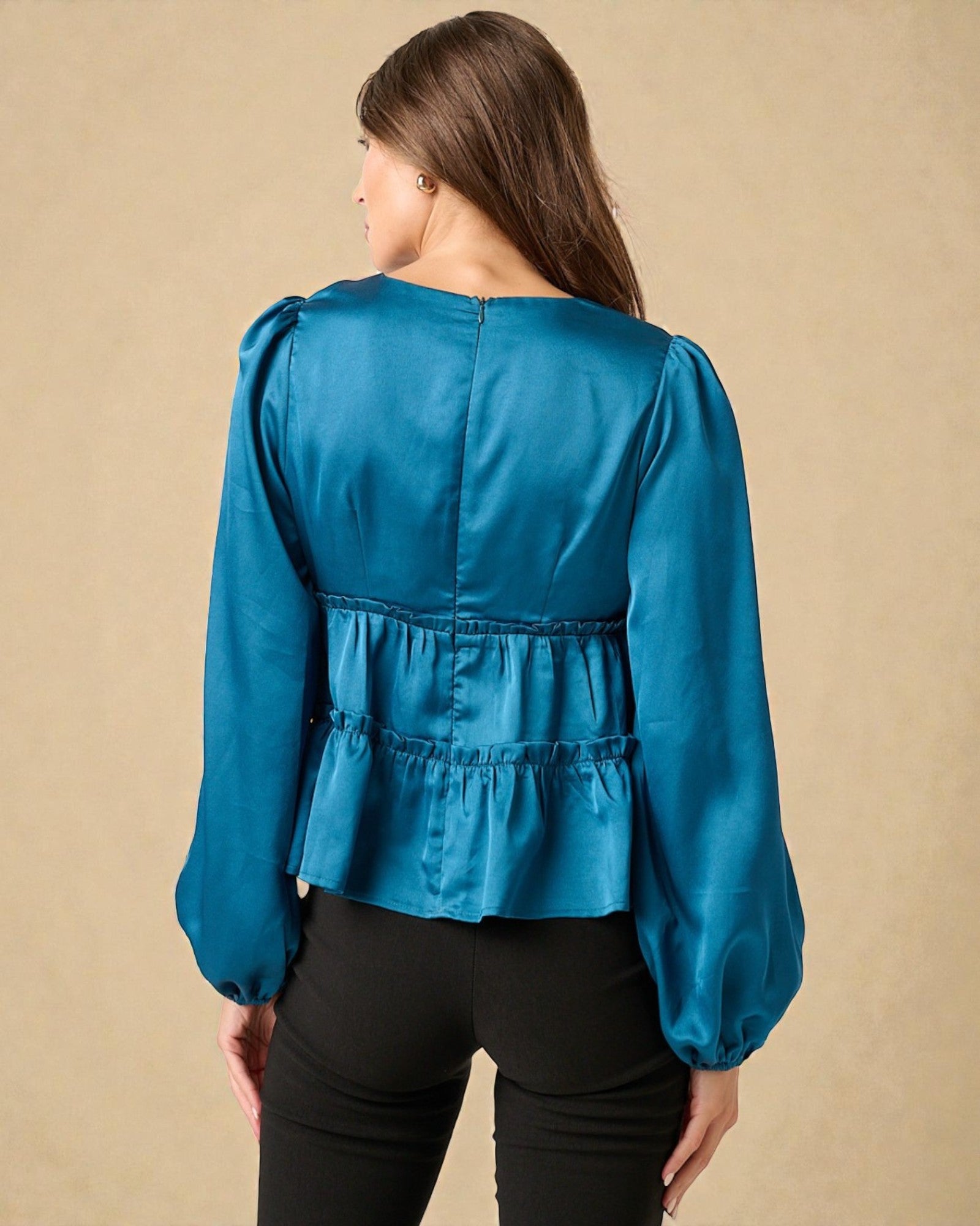 Woman wearing a blue blouse with puffed sleeves against a beige background