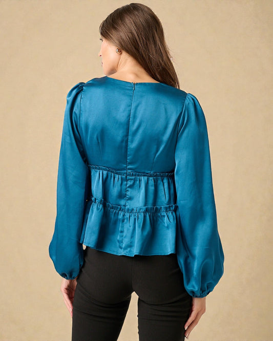 Woman wearing a blue blouse with puffed sleeves against a beige background