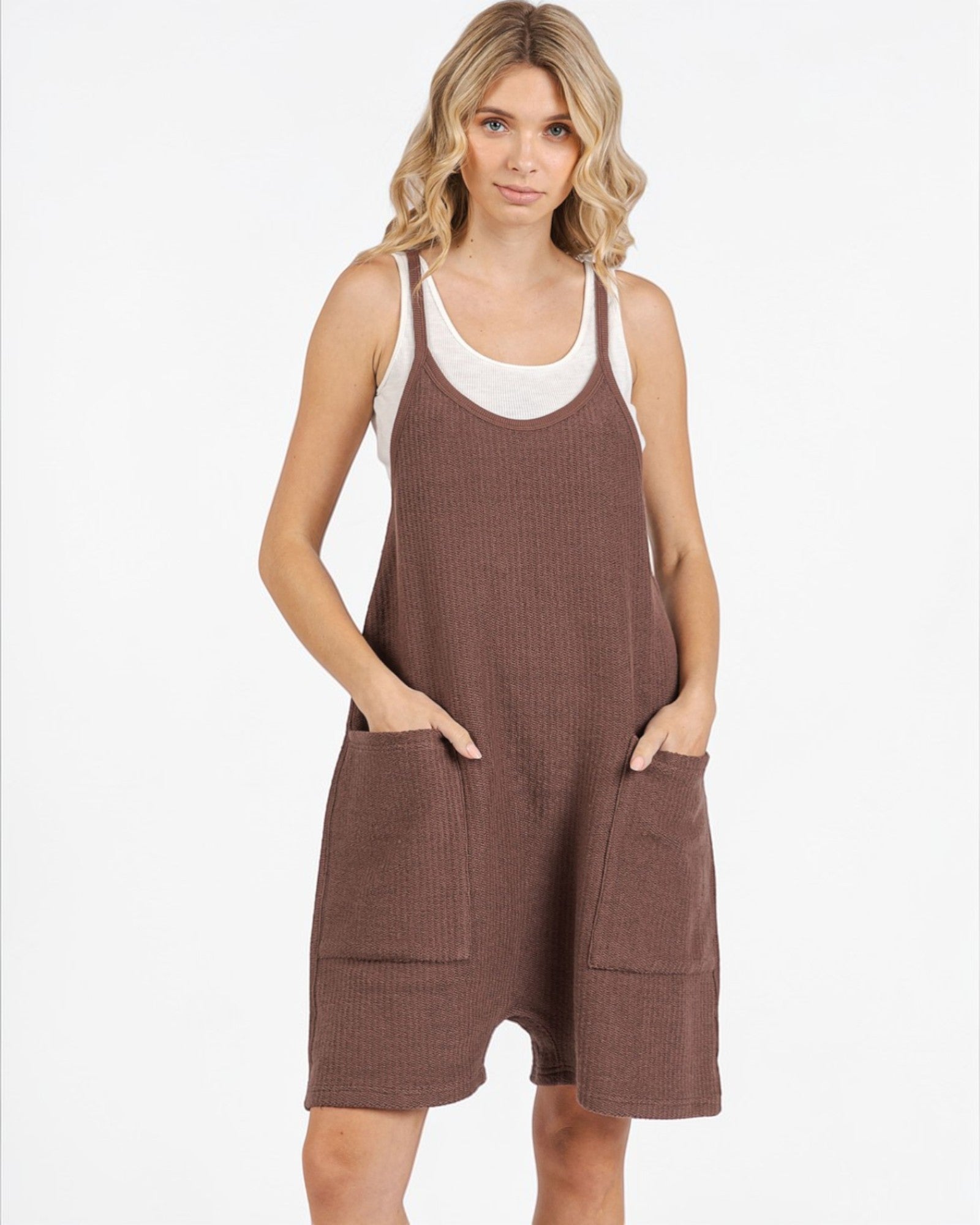 Woman wearing a brown waffle knit dress with pockets on a white background