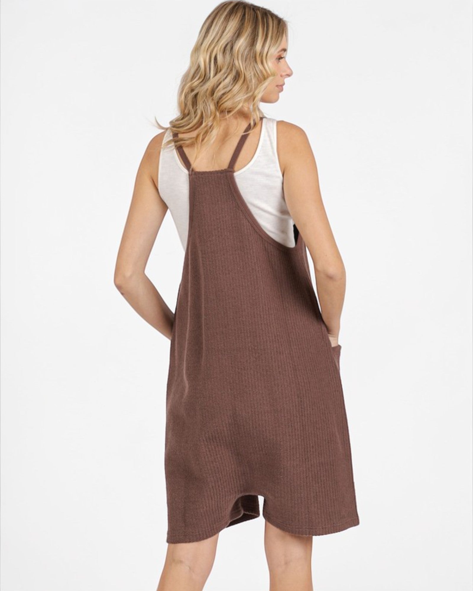 Woman wearing a brown ribbed dress over a white tank top on a white background