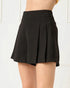 Black pleated shorts worn by a person on a white background