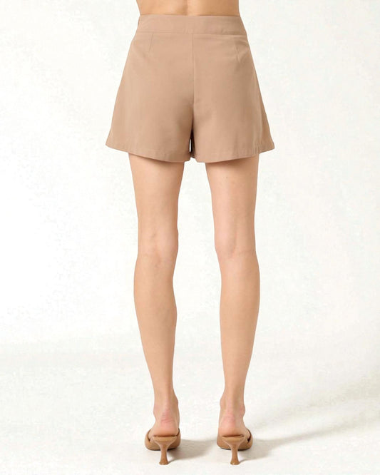 Beige shorts worn by a person on a white background