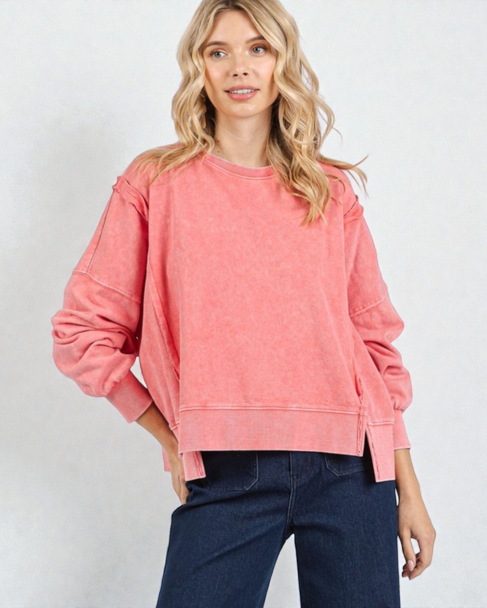 Woman wearing a pink sweatshirt and blue jeans on a white background