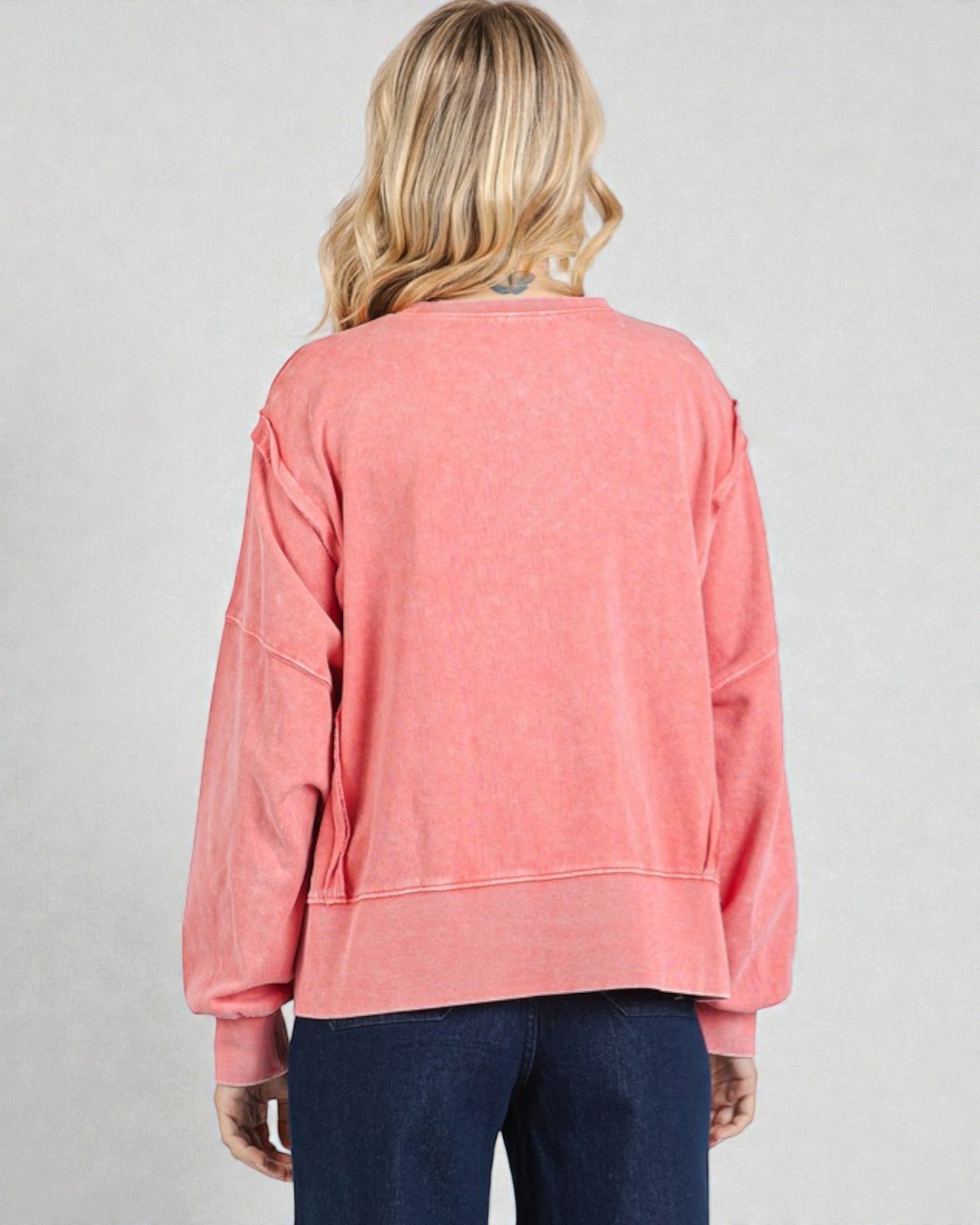 Person wearing a pink sweatshirt on a plain background