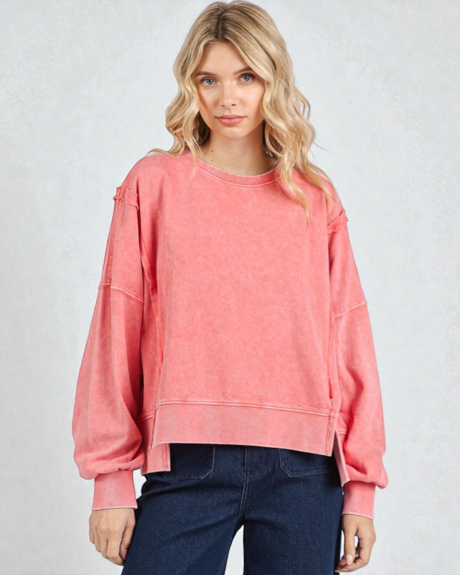 Woman wearing a pink sweatshirt against a plain background