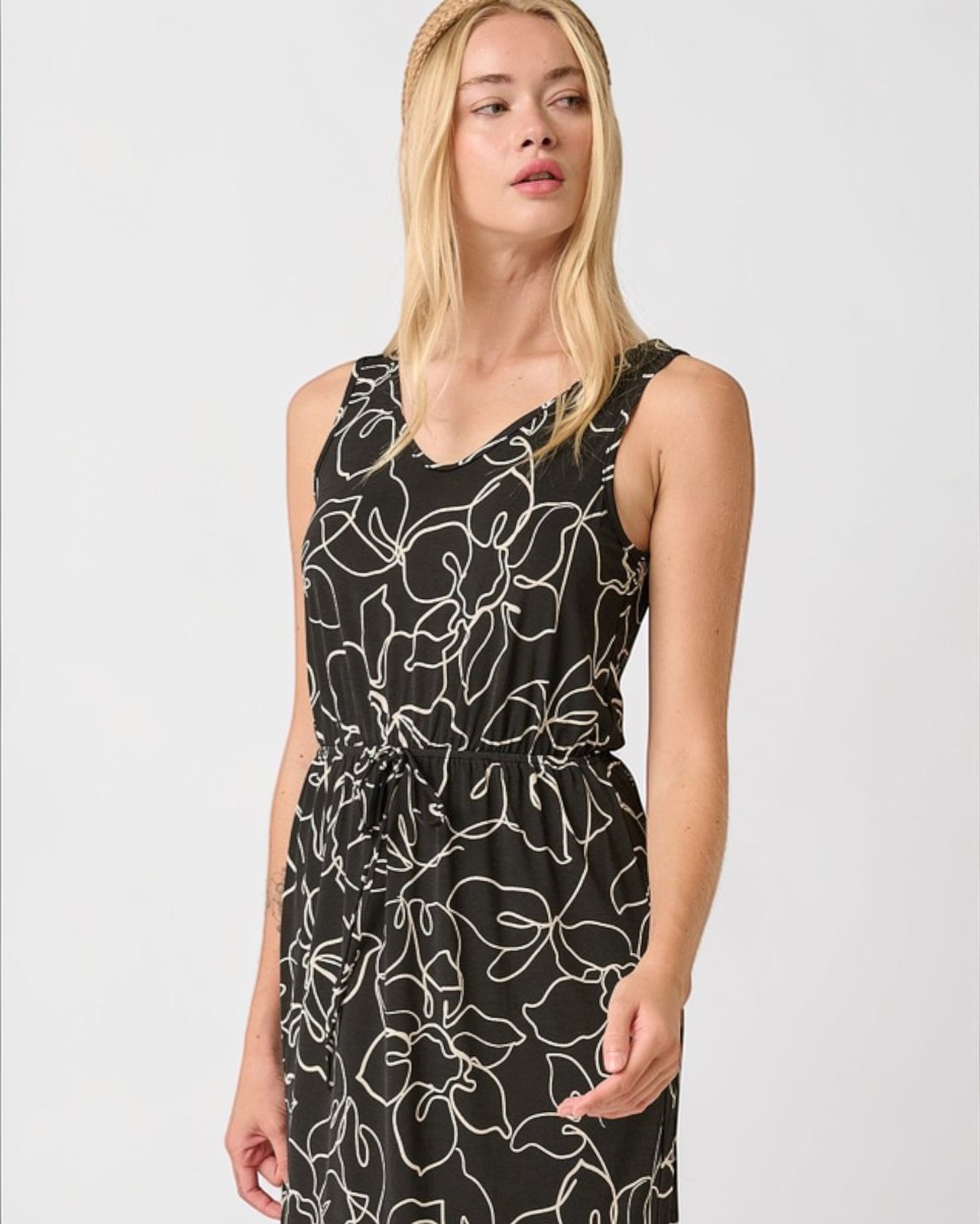 Woman wearing a black dress with white floral pattern on a white background
