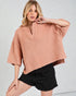 Woman wearing a pink knitted sweater and black shorts on a light gray background