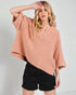 Woman wearing a pink oversized sweater and black shorts on a white background