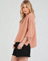 Woman wearing a pink sweater and black skirt on a white background