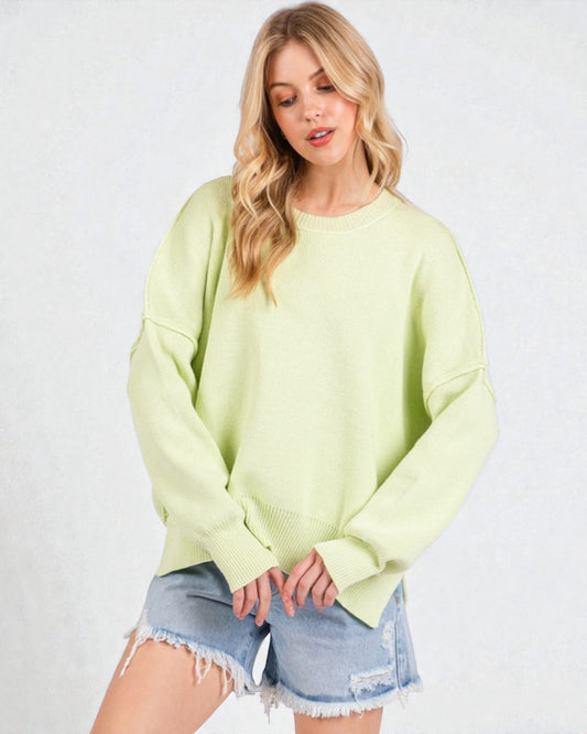 Woman wearing a light green sweater and denim shorts on a white background