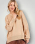 Woman wearing a beige sweater against a plain background