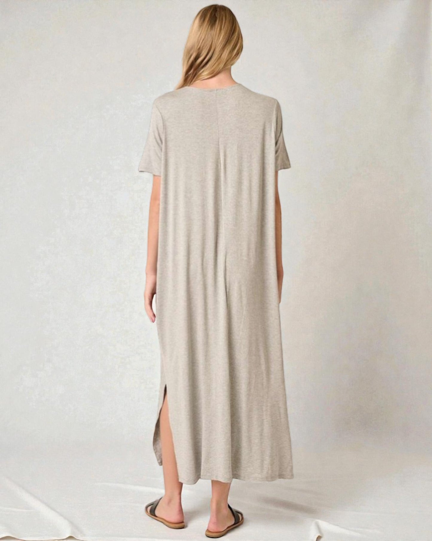 Woman wearing a long beige dress with a slit on a white background