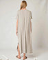 Woman wearing a long beige dress with a slit on a white background