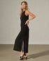 Woman wearing a black sleeveless dress with a slit on a plain background