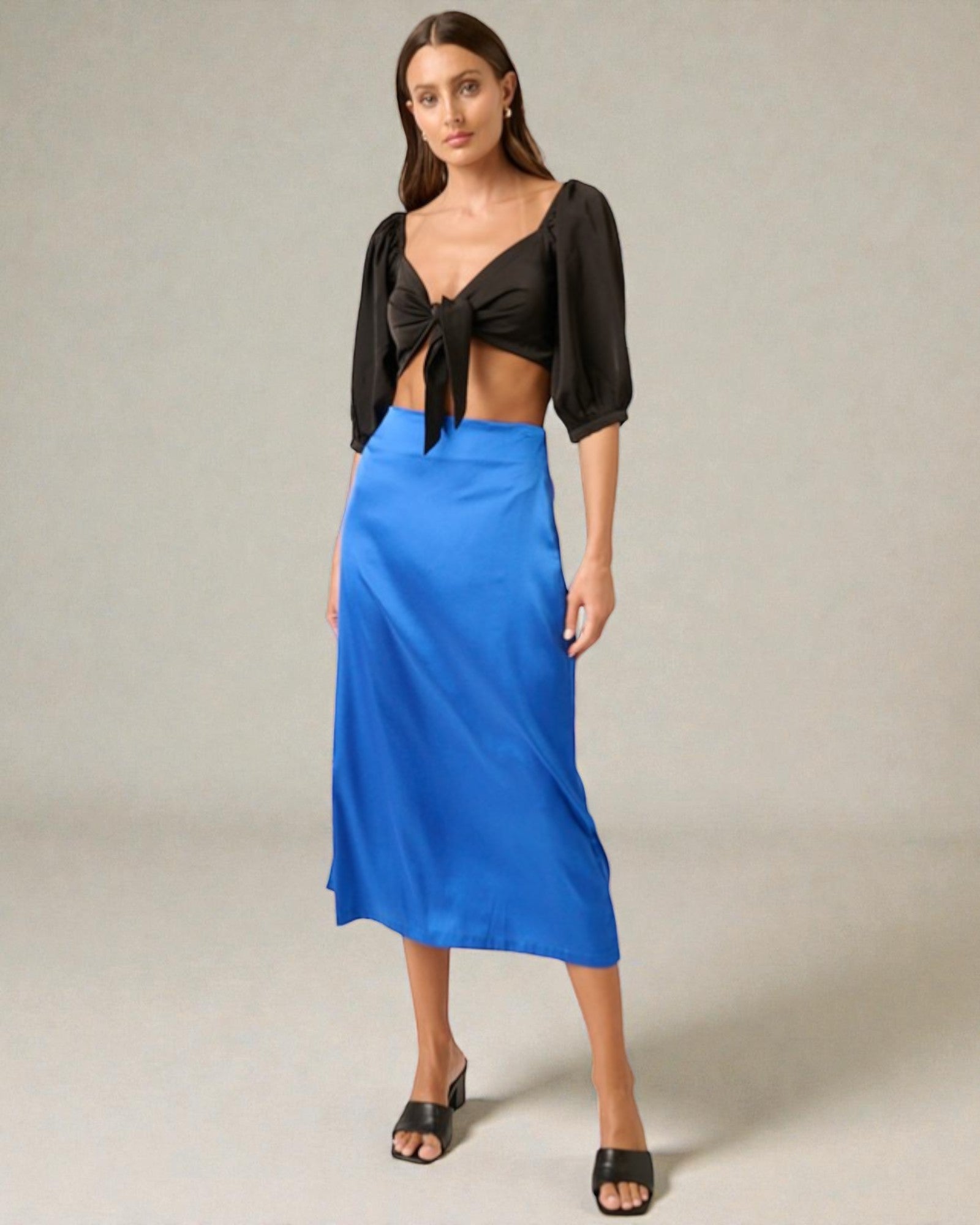 Woman wearing a black top and blue skirt on a plain background