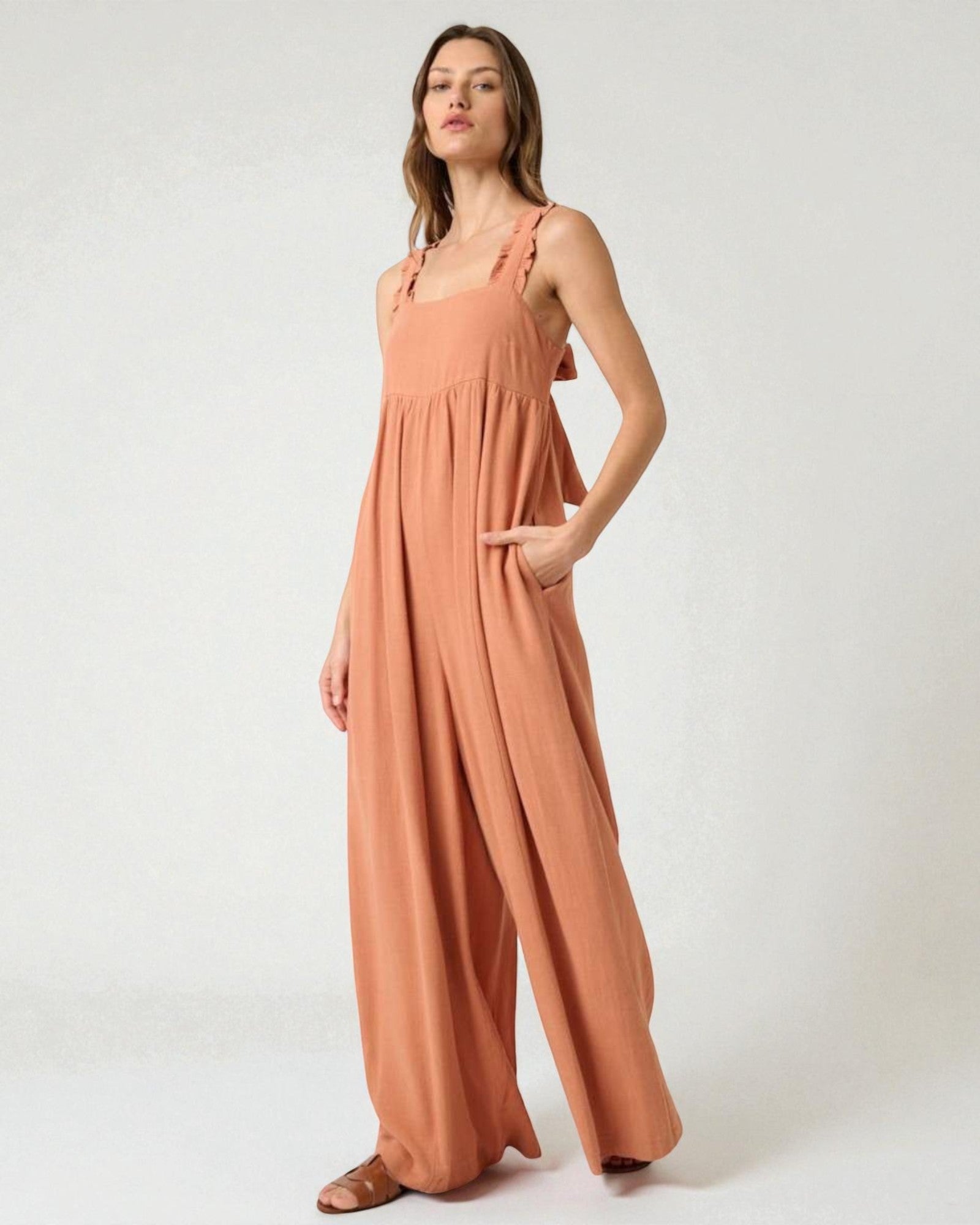 Woman wearing a peach-colored jumpsuit on a white background