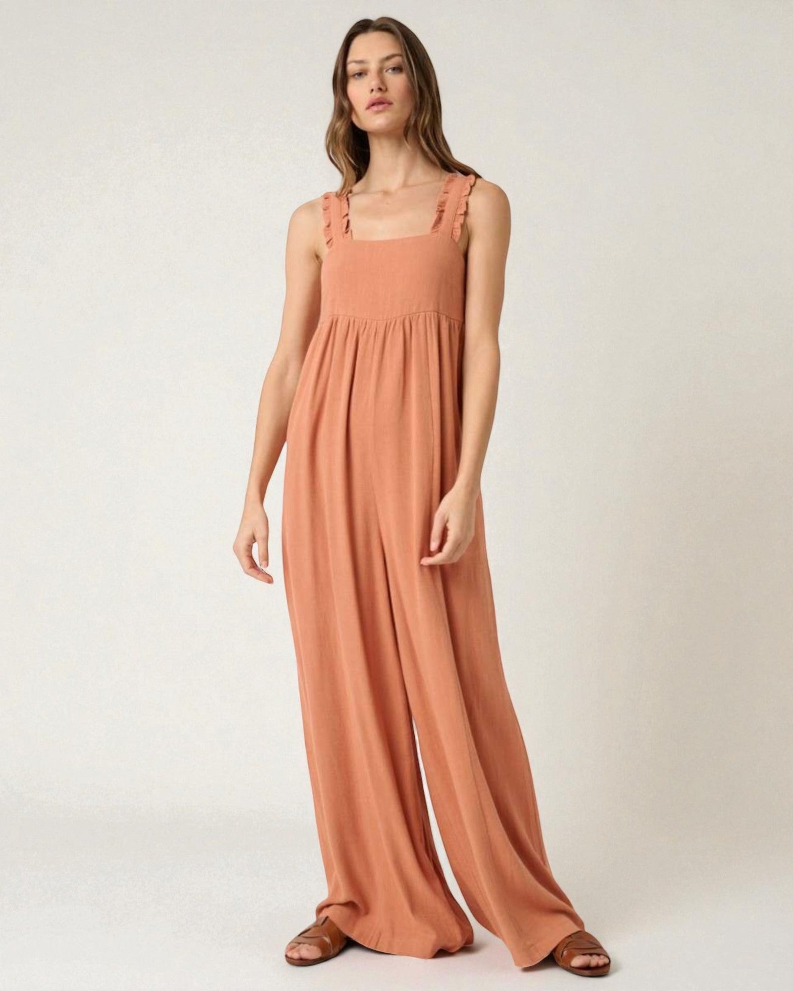 Woman wearing a long peach dress against a white background