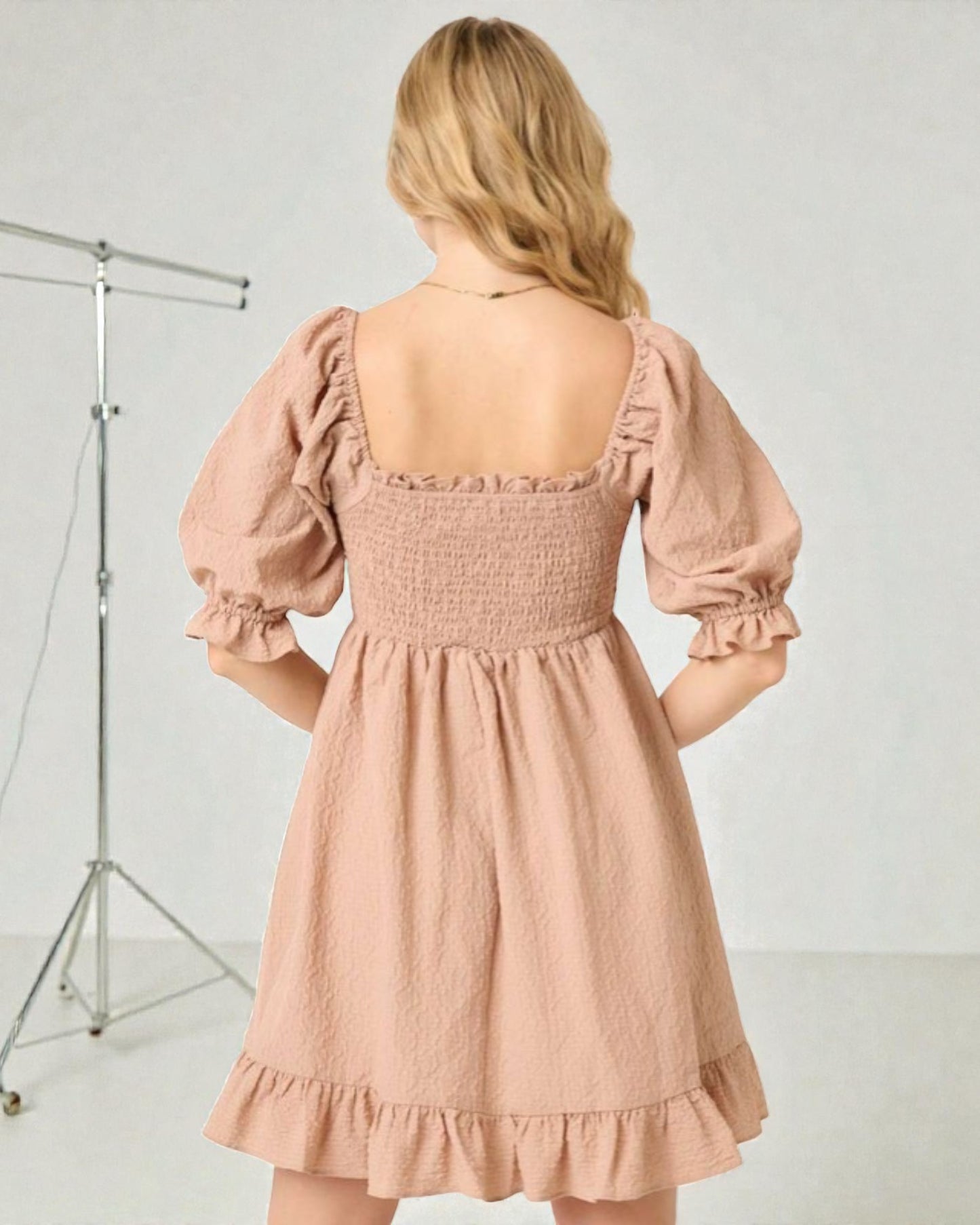 Woman wearing a pink dress with puff sleeves against a white background