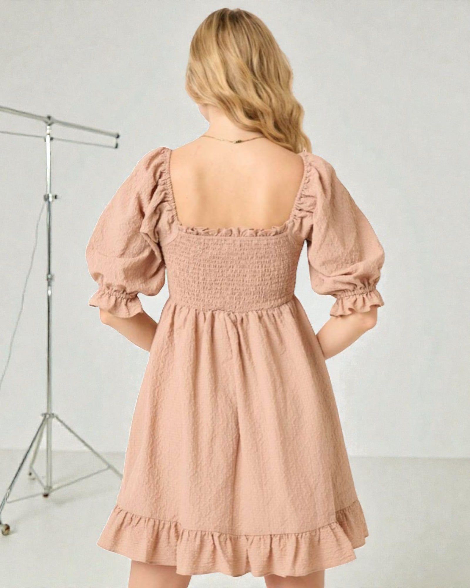 Woman wearing a pink dress with puff sleeves against a white background