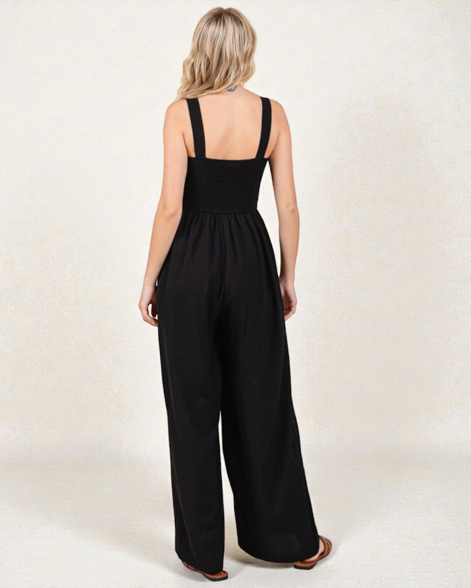 Woman wearing a black jumpsuit on a plain background