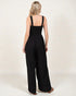 Woman wearing a black jumpsuit on a plain background