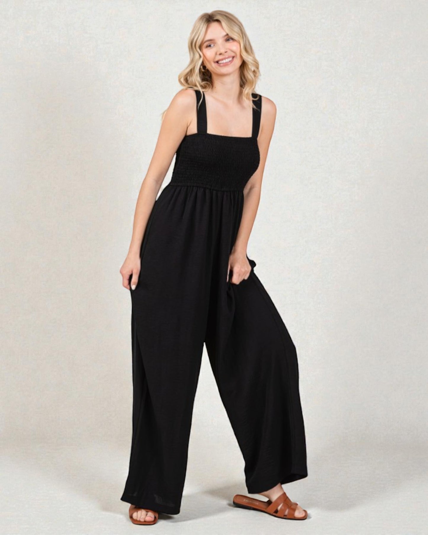 Woman wearing a black jumpsuit against a plain background