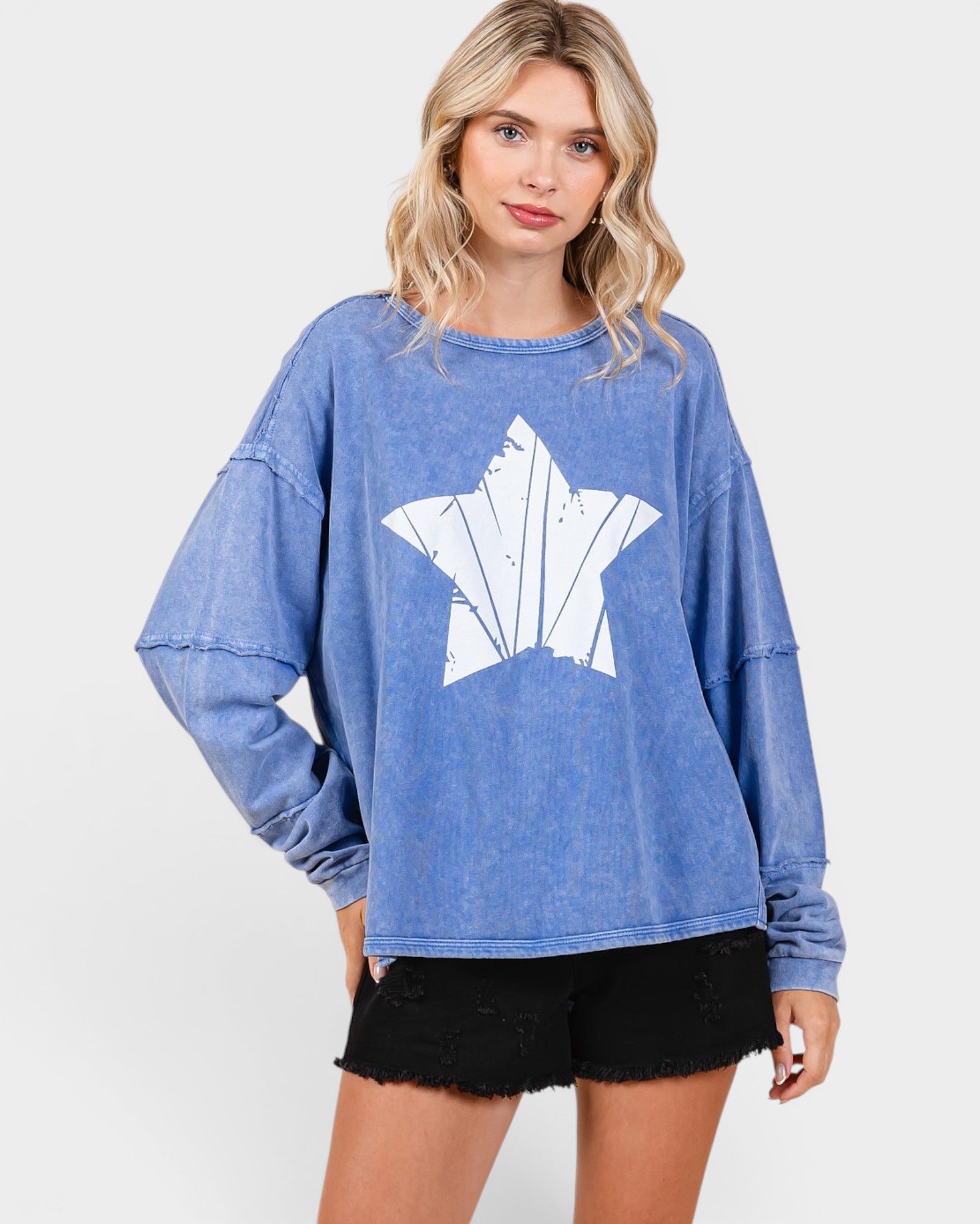 Woman wearing a blue sweatshirt with a white graphic design on a plain background