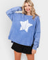 Woman wearing a blue sweatshirt with a white graphic design on a plain background
