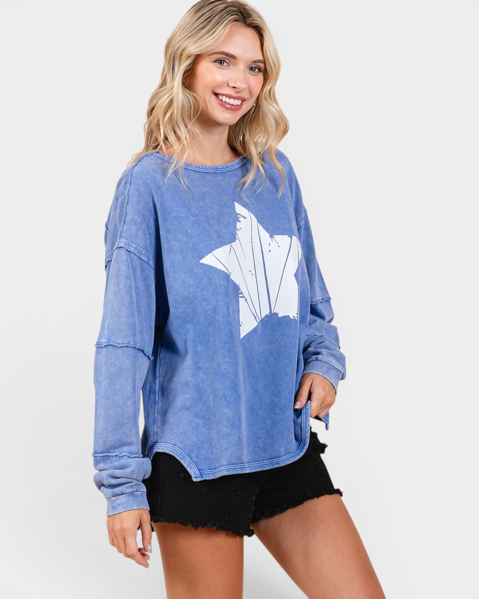 Woman wearing a blue sweatshirt with a white graphic on a plain background