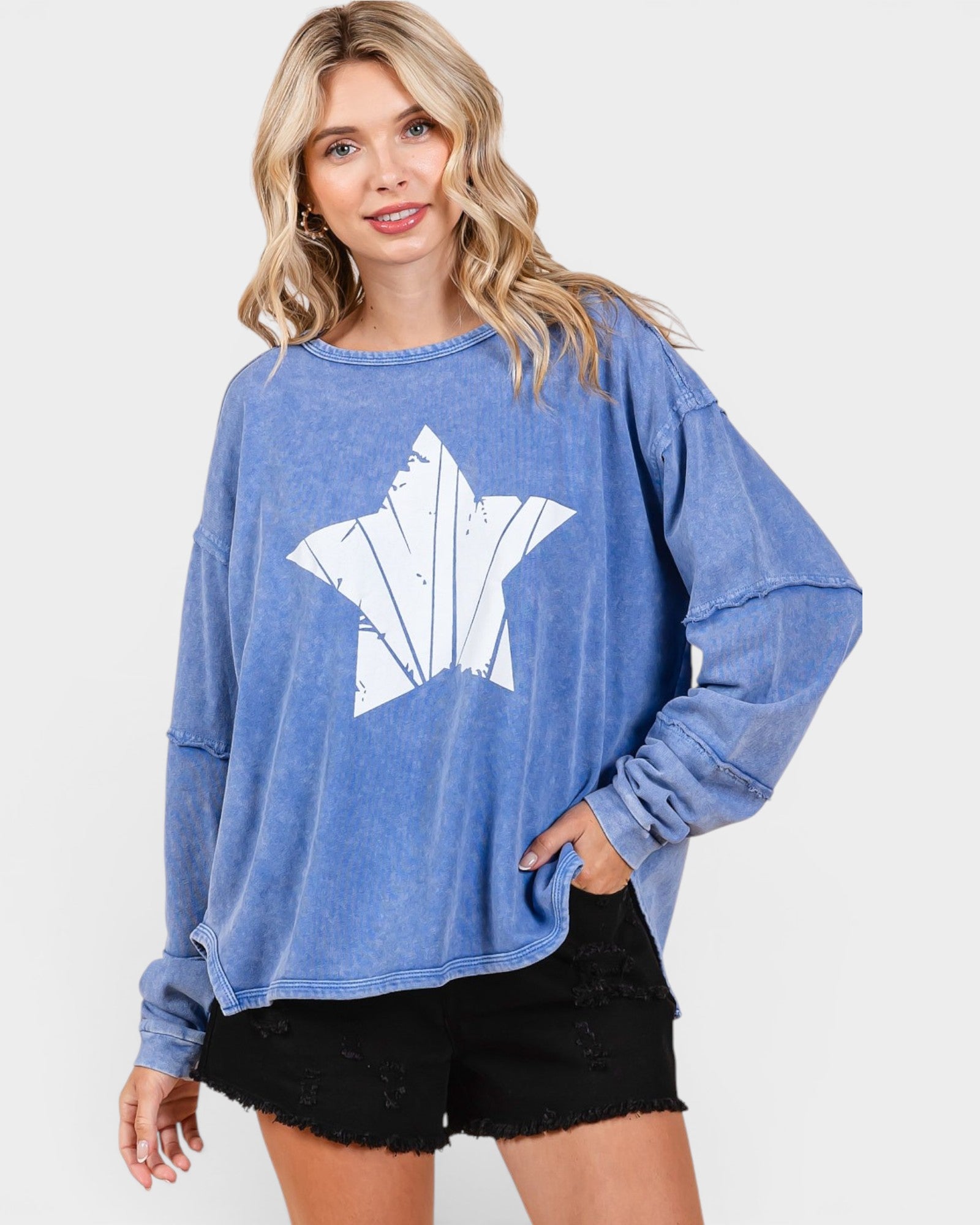 Woman wearing a blue sweatshirt with a white graphic design on a plain background