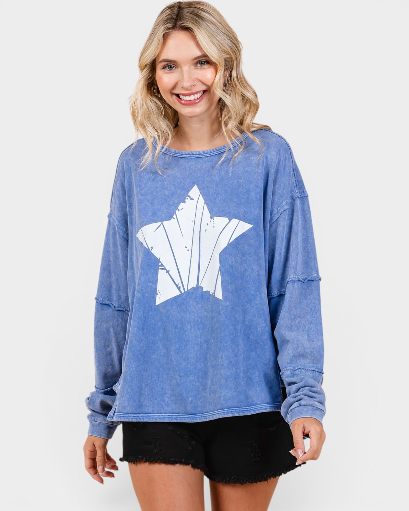 Woman wearing a blue sweatshirt with a white star design on a white background
