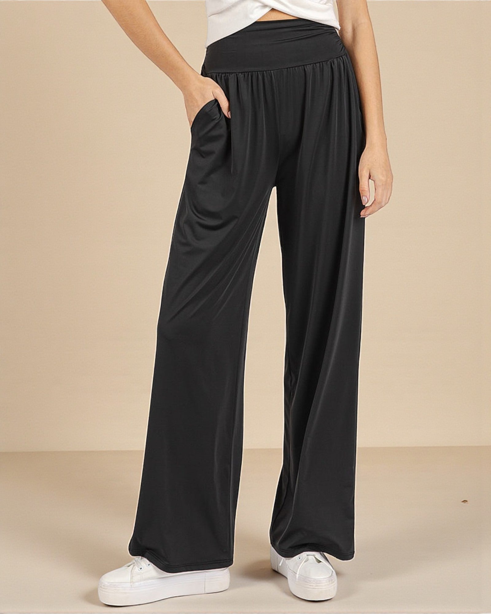 Person wearing black wide-leg pants on a beige background