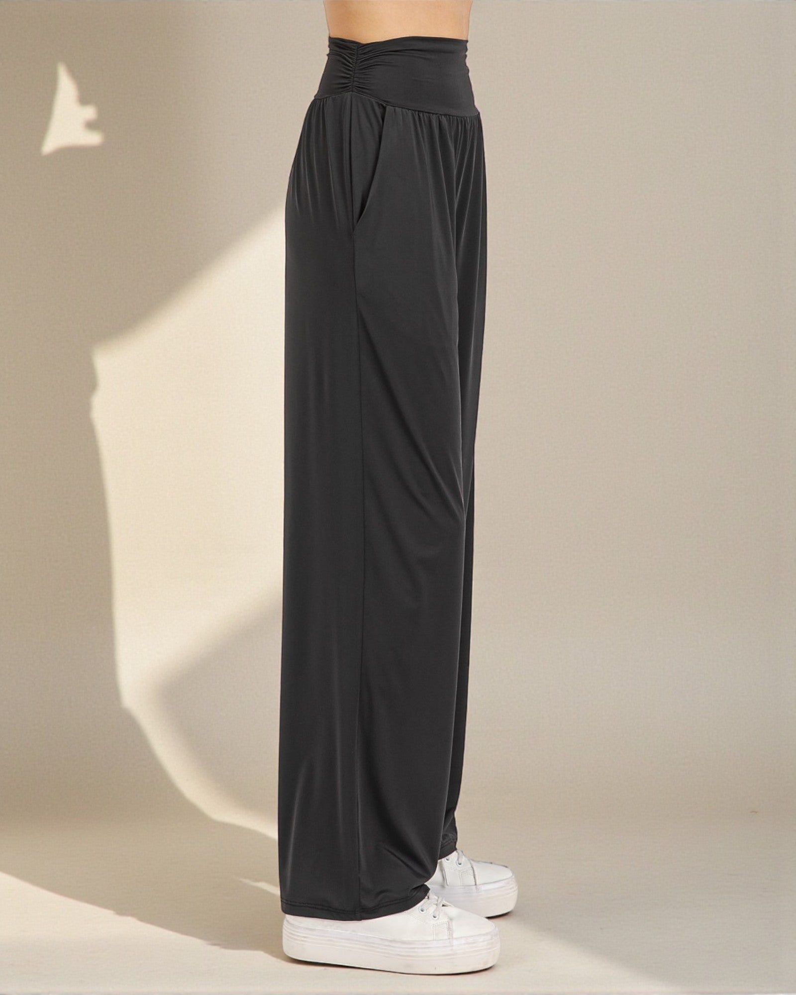 Black wide-leg pants worn by a person on a beige background
