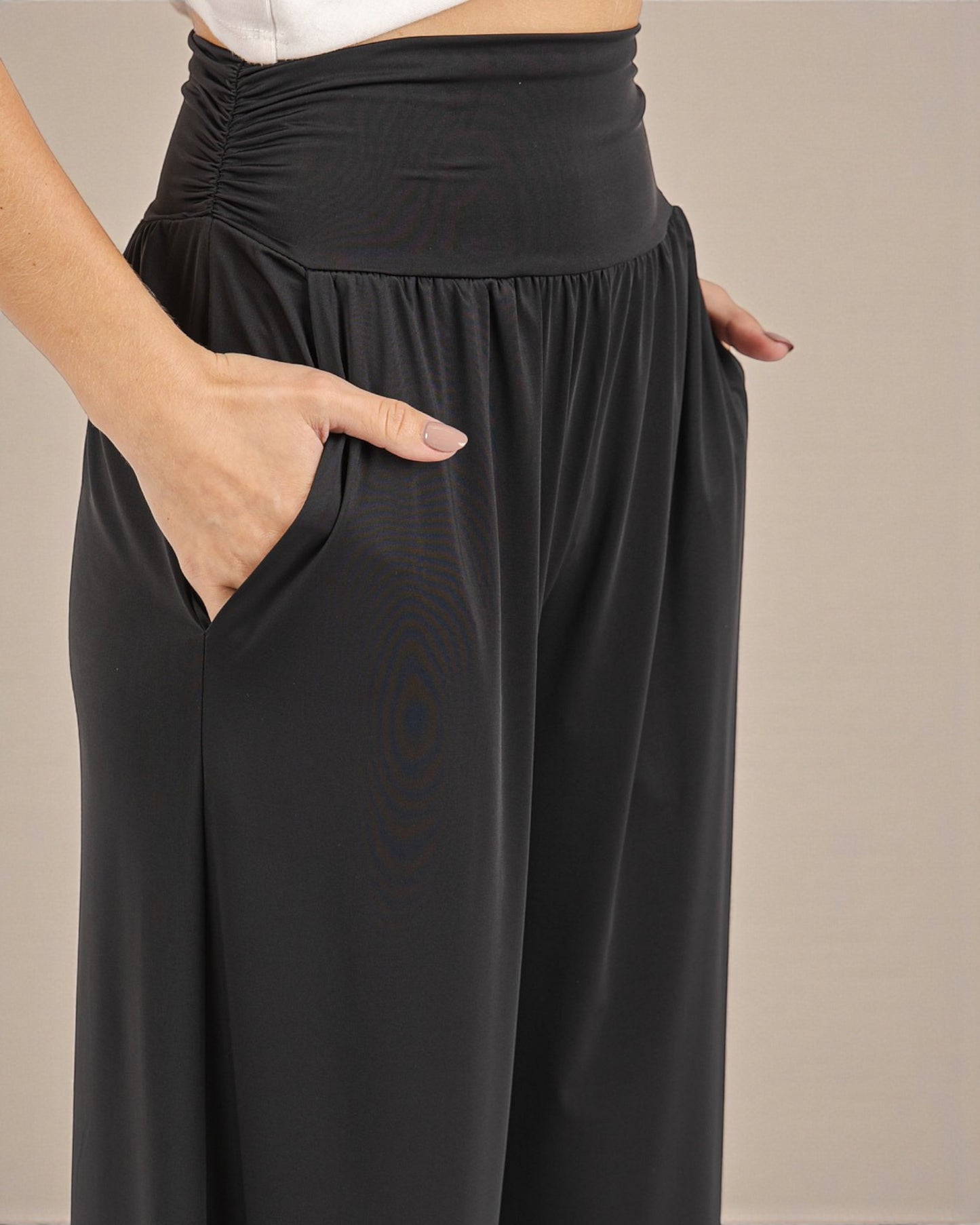 Black wide-leg pants worn by a person on a beige background