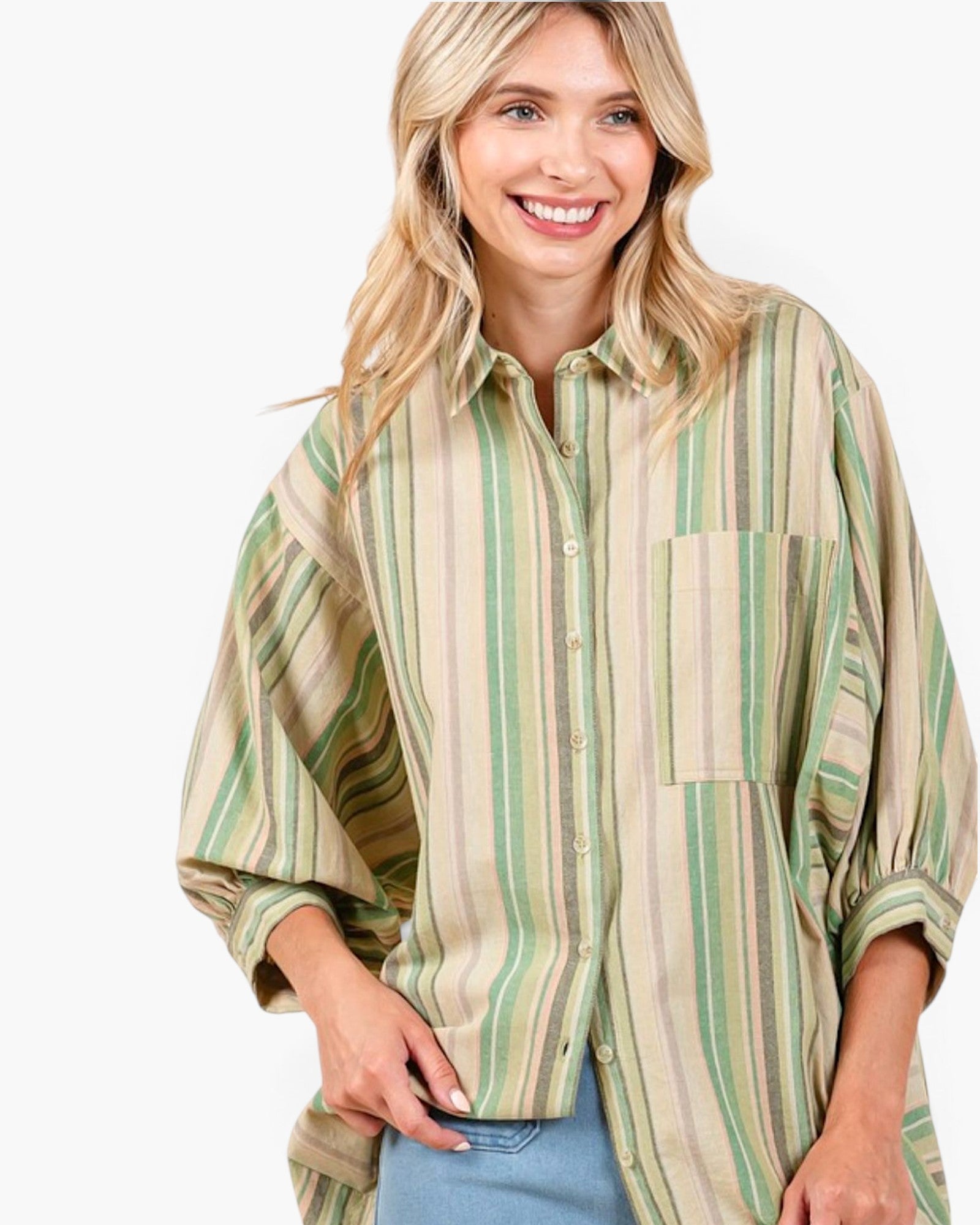 A smiling blonde woman wearing a loose button-up shirt with vertical stripes in sage green, olive, and beige, paired with light blue jeans, against a plain white background.
