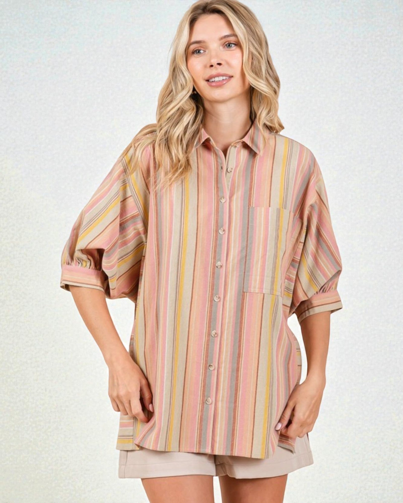 Woman wearing a striped shirt and shorts on a light background