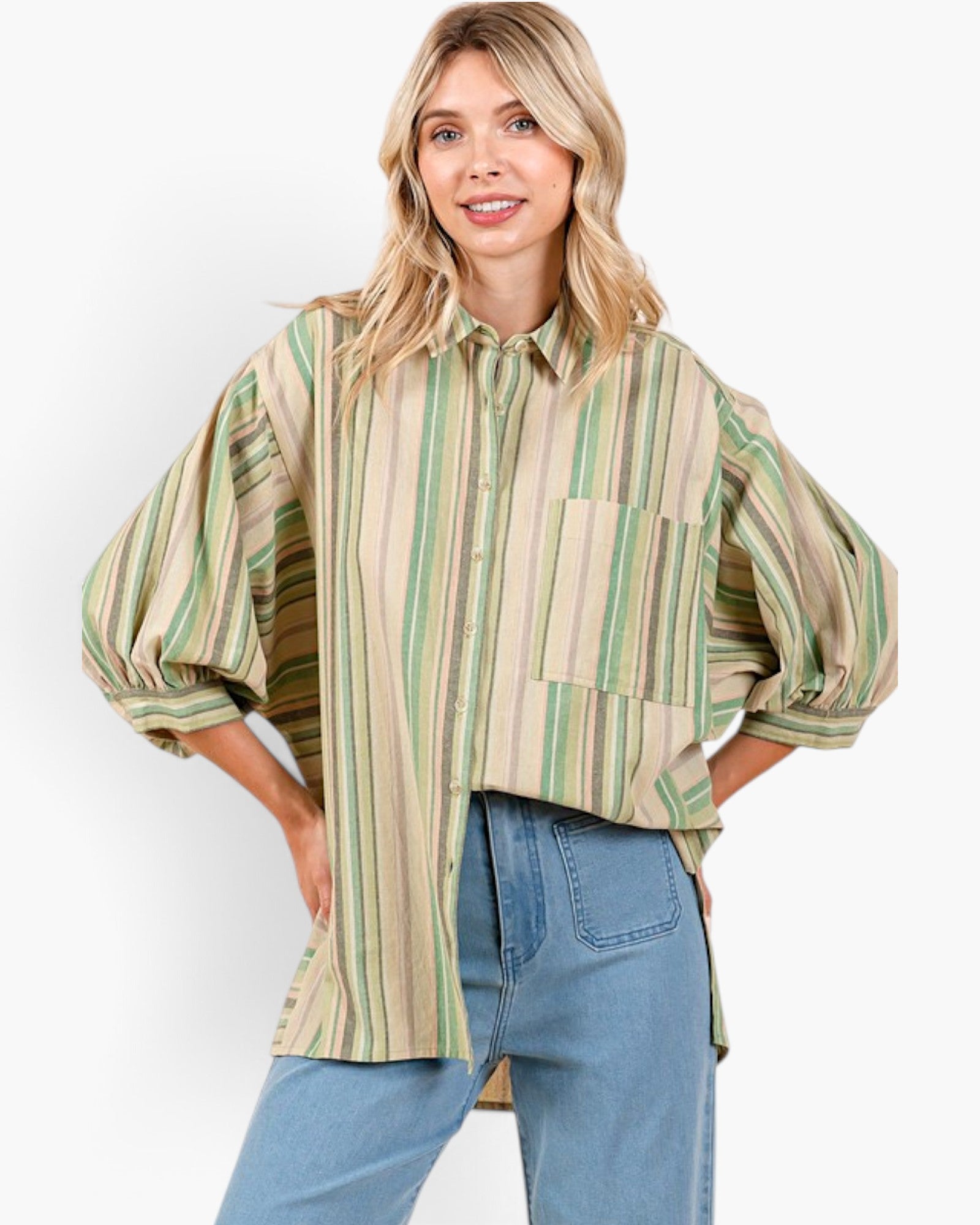 A woman modeling a loose, oversized button-up shirt with vertical stripes in beige, green, and brown, paired with light blue jeans against a plain white background.