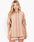 A woman modeling a pastel striped button-up shirt with puff sleeves and beige shorts against a plain white studio background.