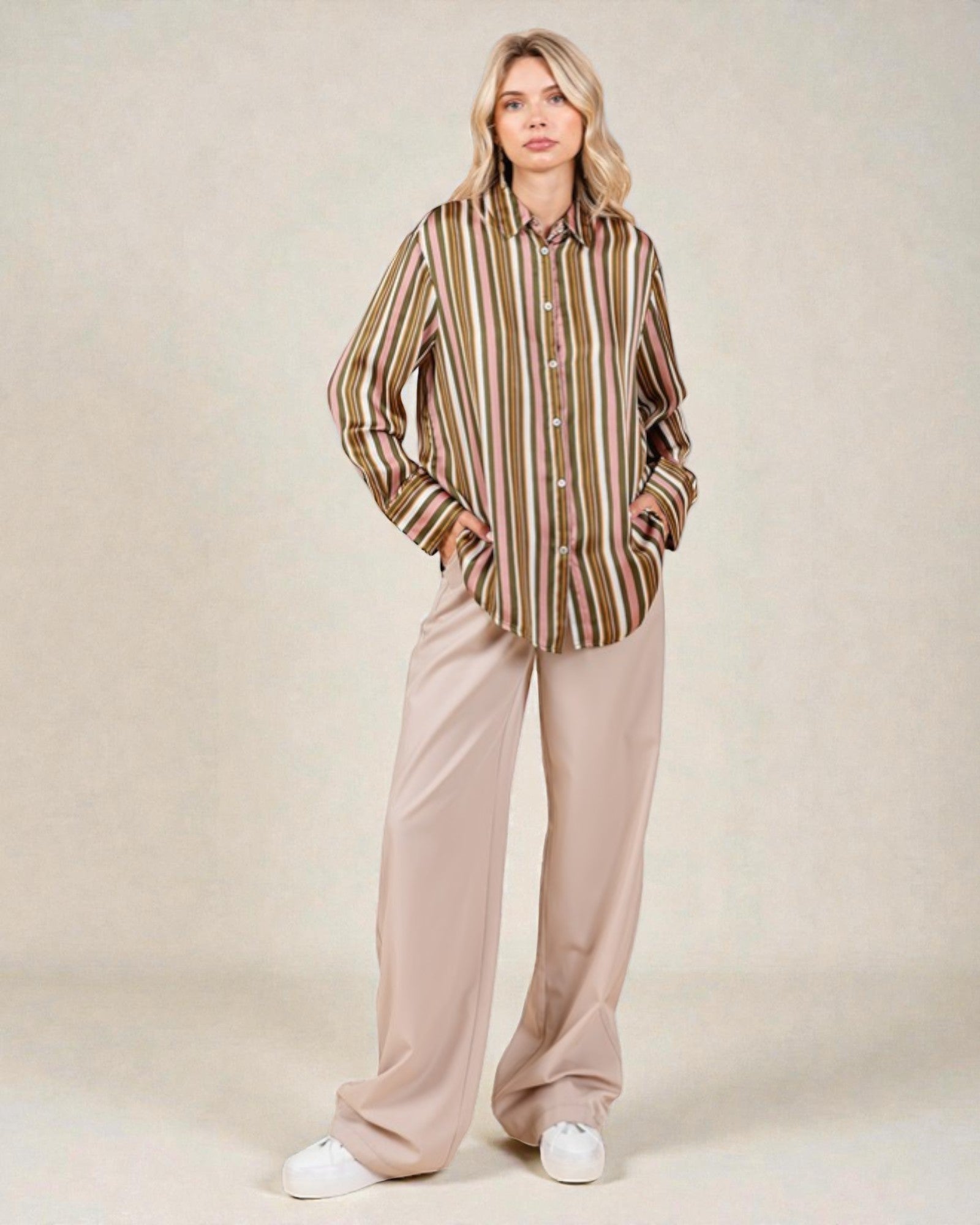 Woman wearing a striped shirt and beige pants on a plain background