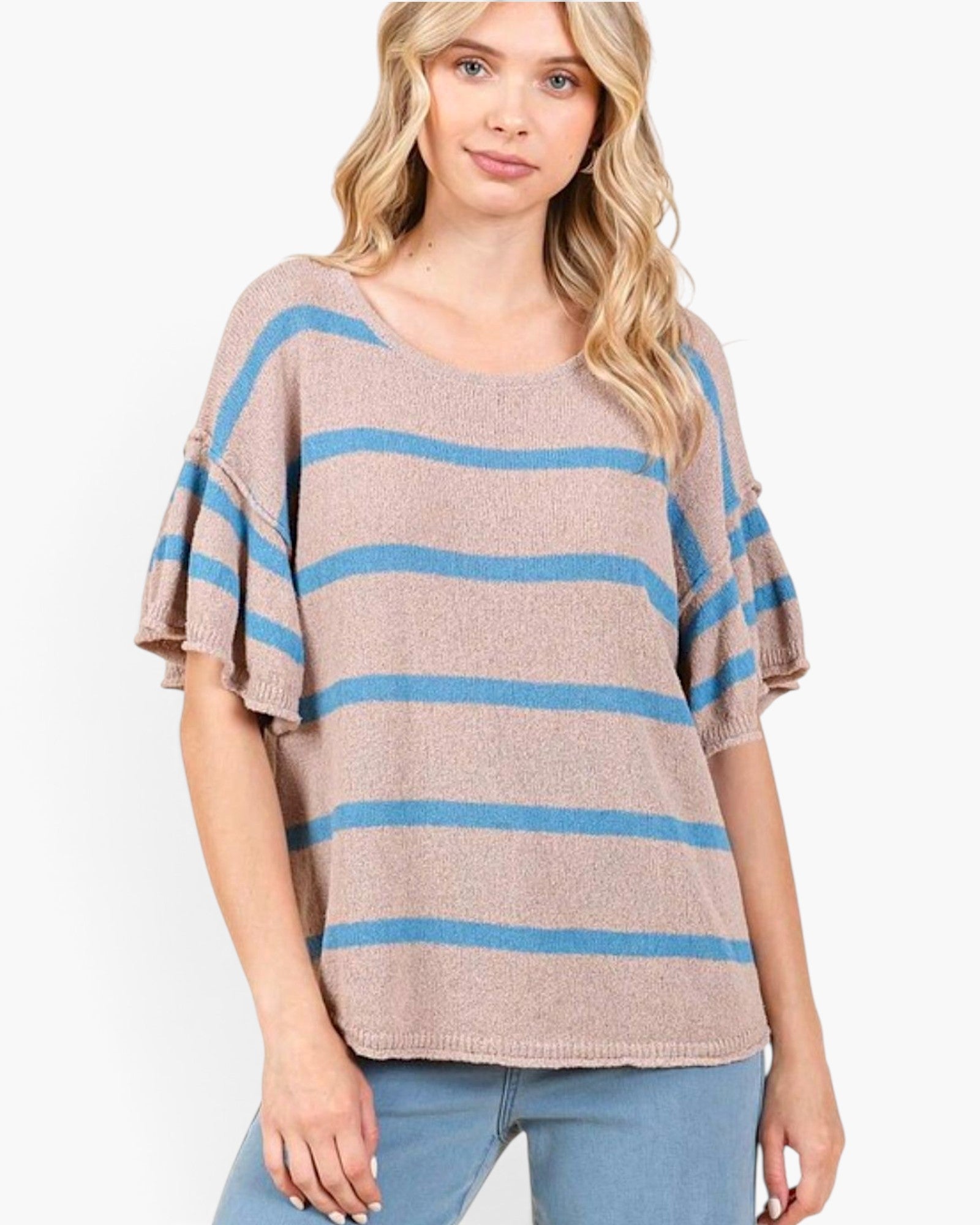 A woman wearing a loose, short-sleeve knit top with horizontal blue stripes on a taupe background, paired with light blue jeans, against a plain white studio background.