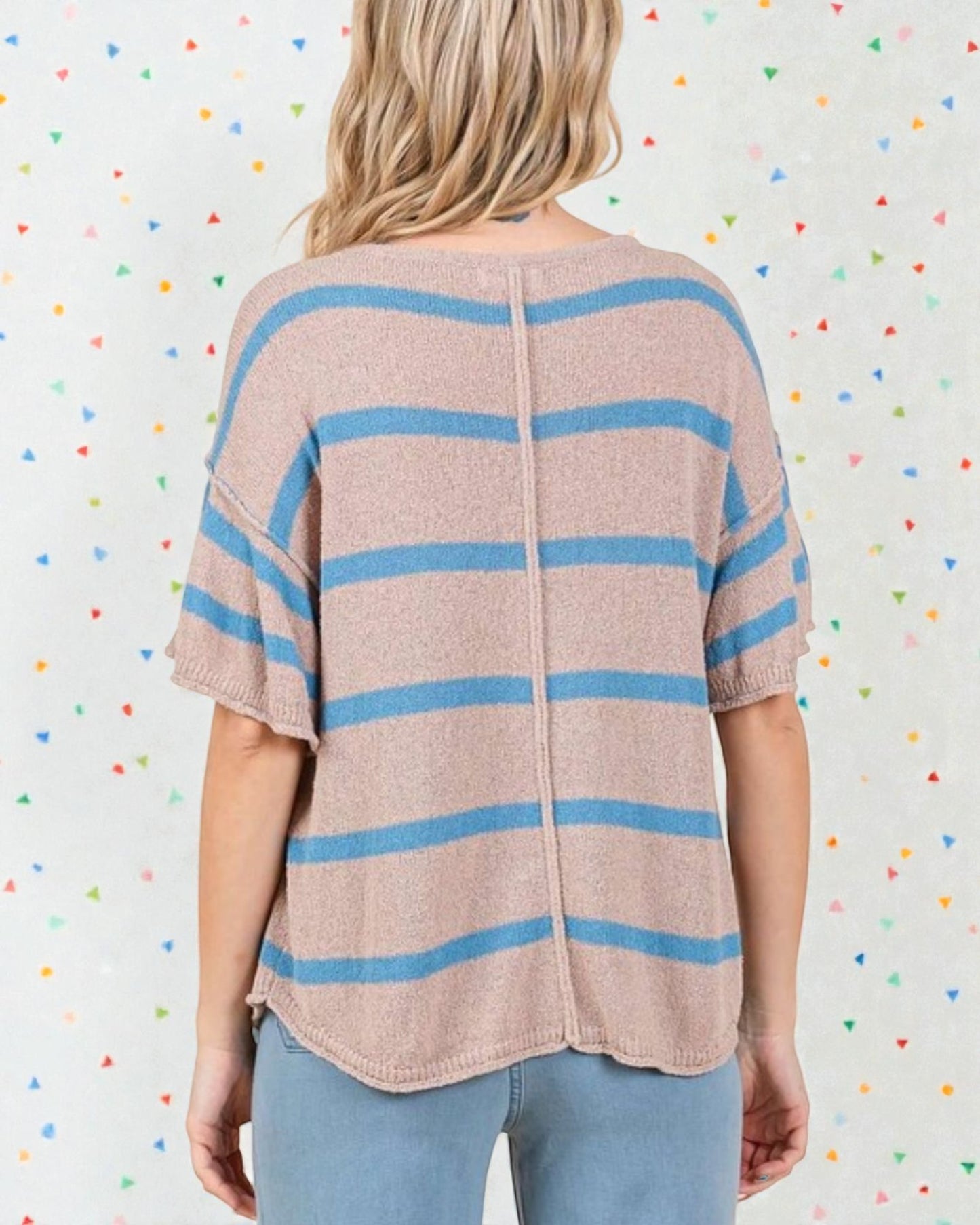 Person wearing a beige and blue striped sweater against a colorful polka dot background