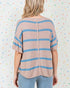 Person wearing a beige and blue striped sweater against a colorful polka dot background