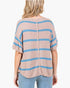 A woman shown from the back wearing a loose, short-sleeve knit top with horizontal light blue stripes on a heathered beige-pink base, paired with light blue jeans against a plain white background.