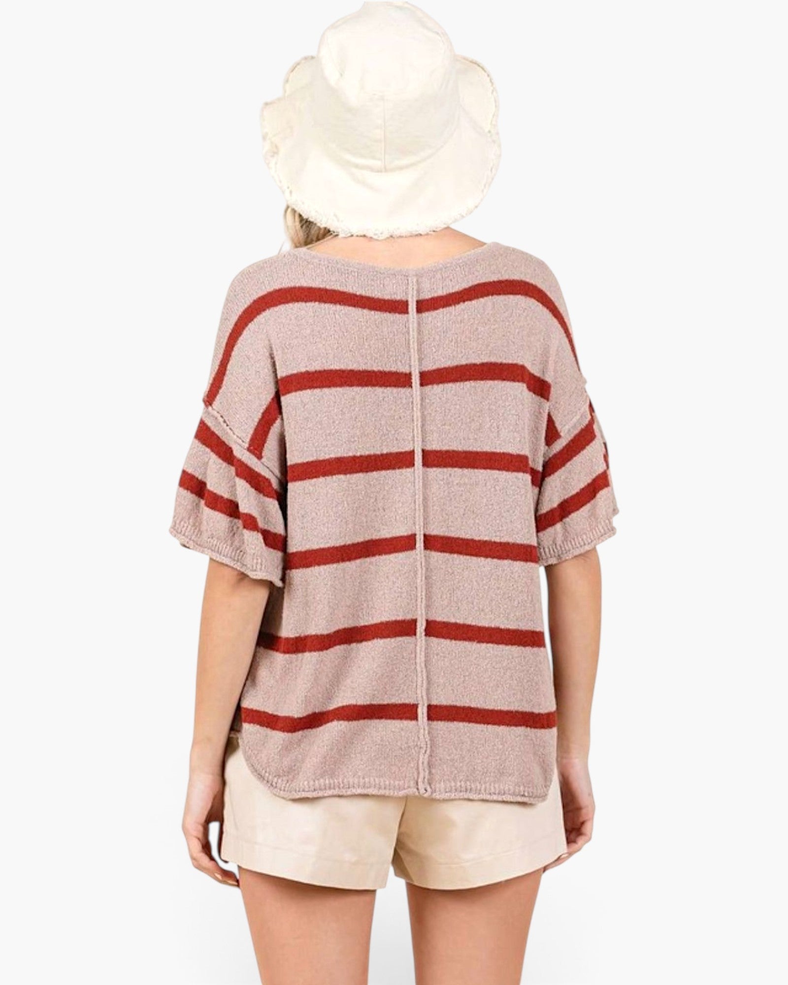A model shown from the back wearing a beige knit top with horizontal rust red stripes, paired with beige shorts and a white bucket hat, against a plain white background.