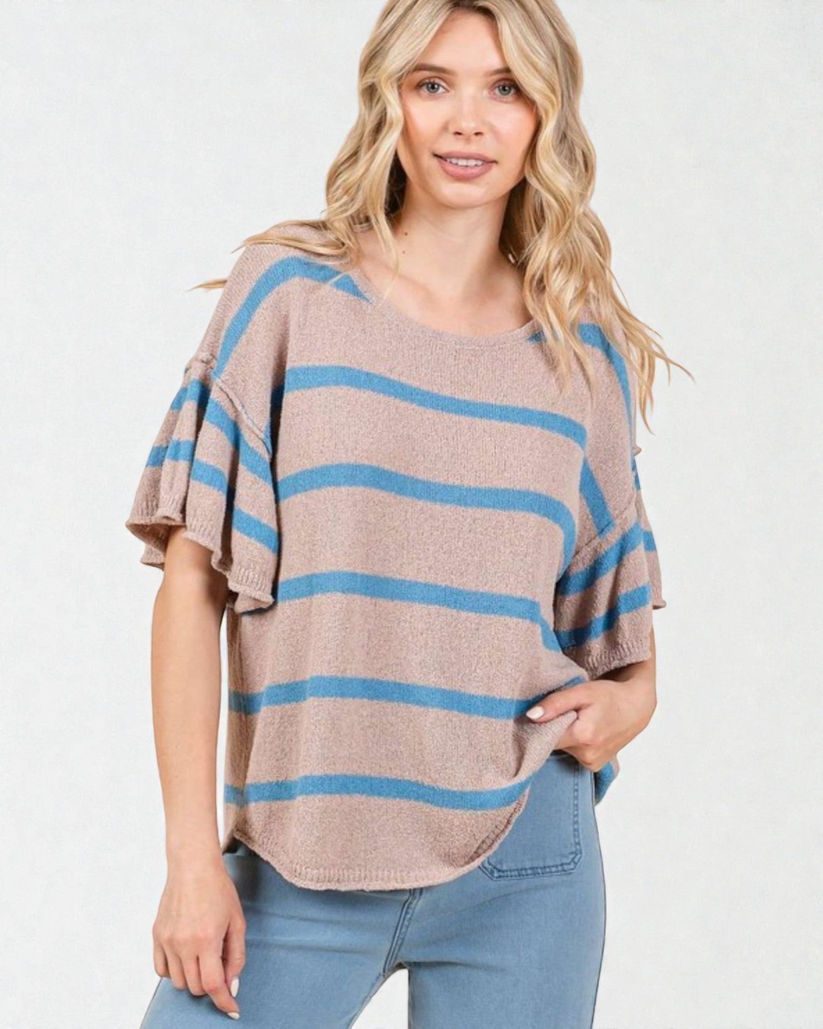 Woman wearing a beige and blue striped sweater with a plain background